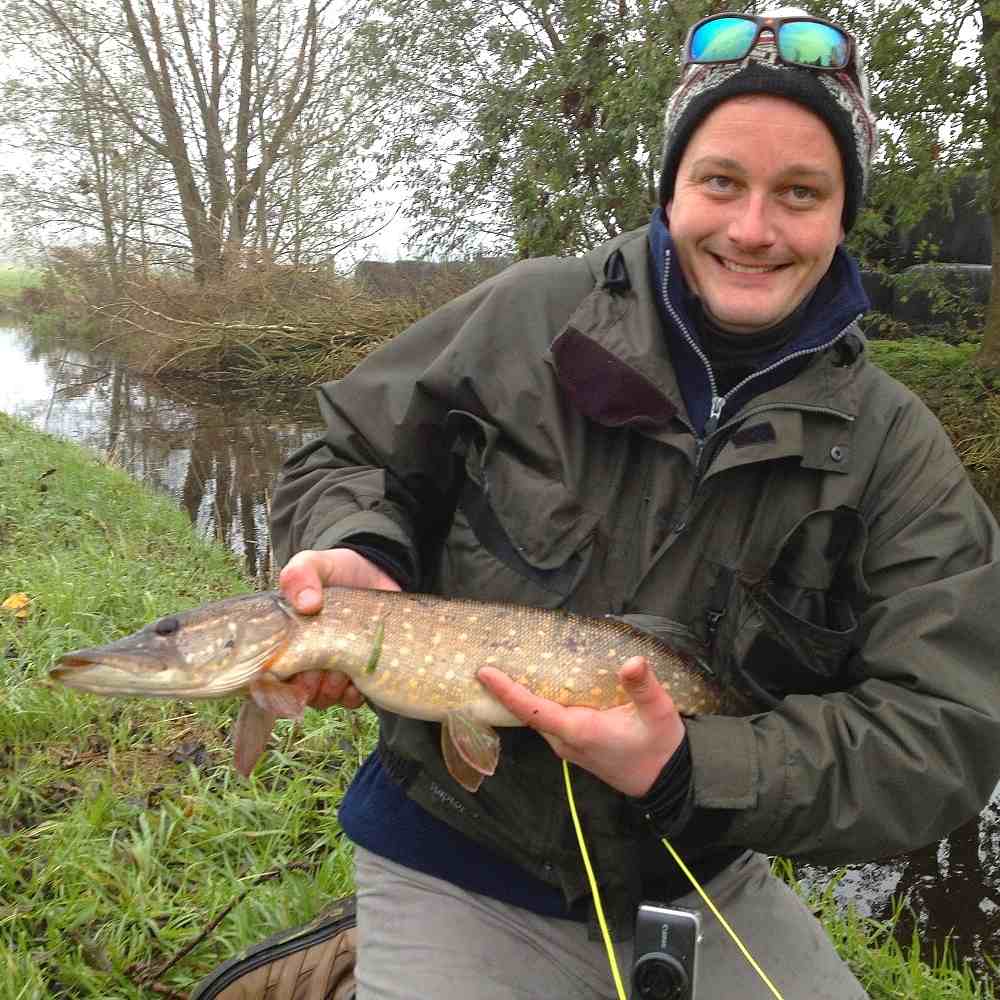 zu sehen ist ein Fliegenfischer mit einem Fisch in den Händen