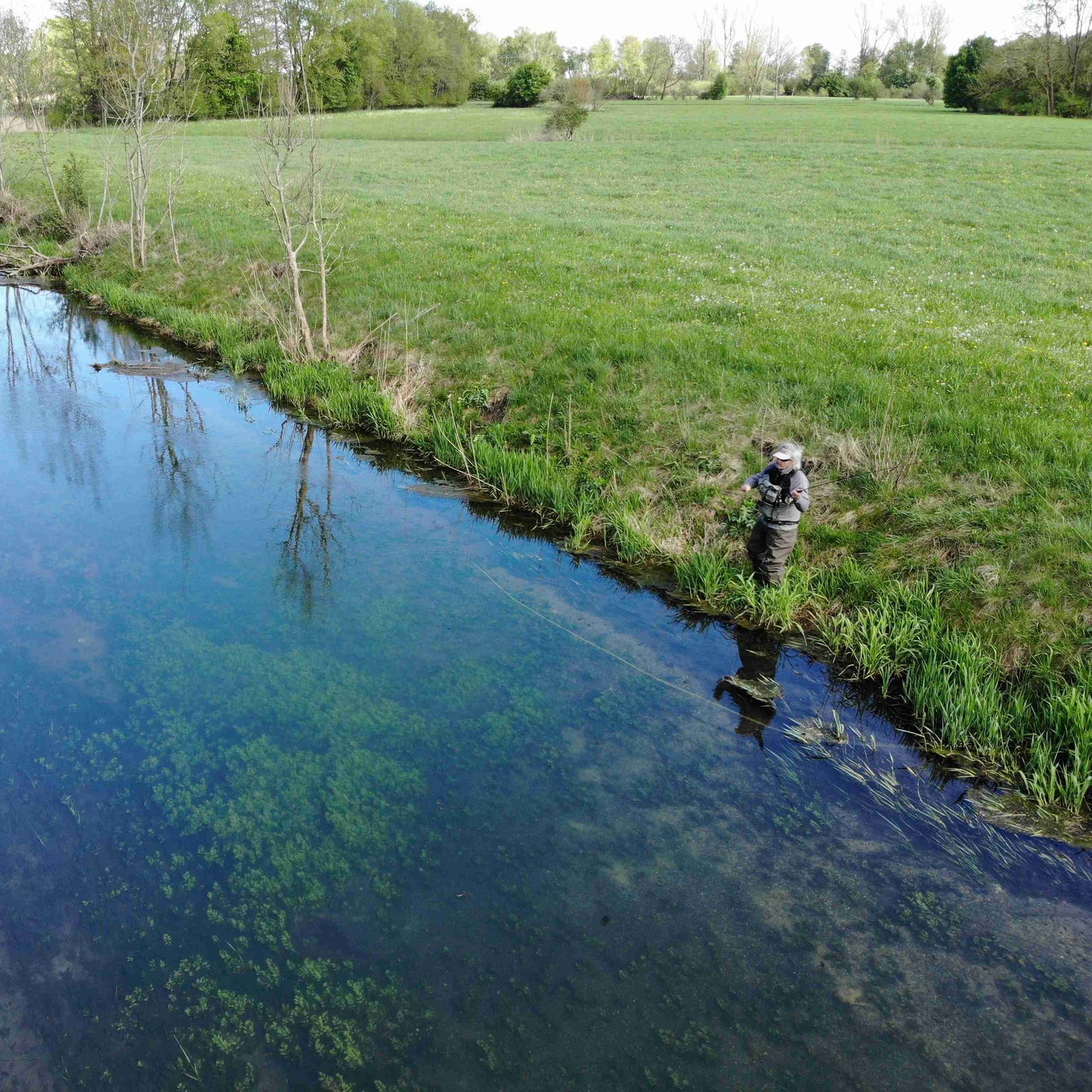 Luftaufnahme von einem Fliegenfischer am Bach