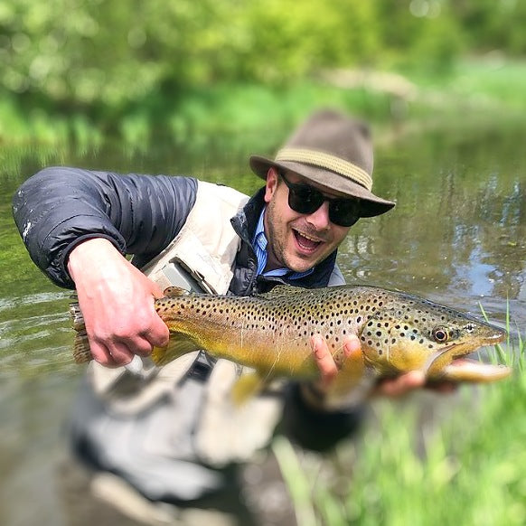Ein Fänger am Bach zeigt seine Forelle