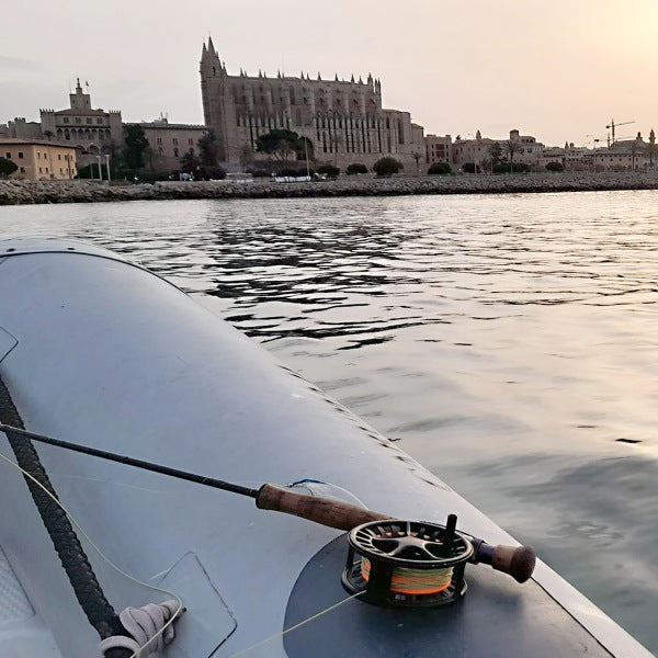 zu sehen ist eine Fliegenrute auf einem Boot im Wasser, im Hintergrund eine Kathedrale