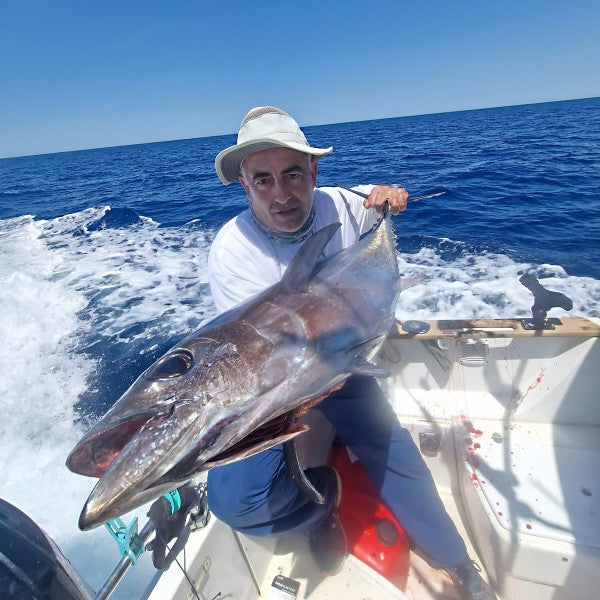 zu sehen ist ein Fischer im Boot, der einen großenn Fisch vor sich hält