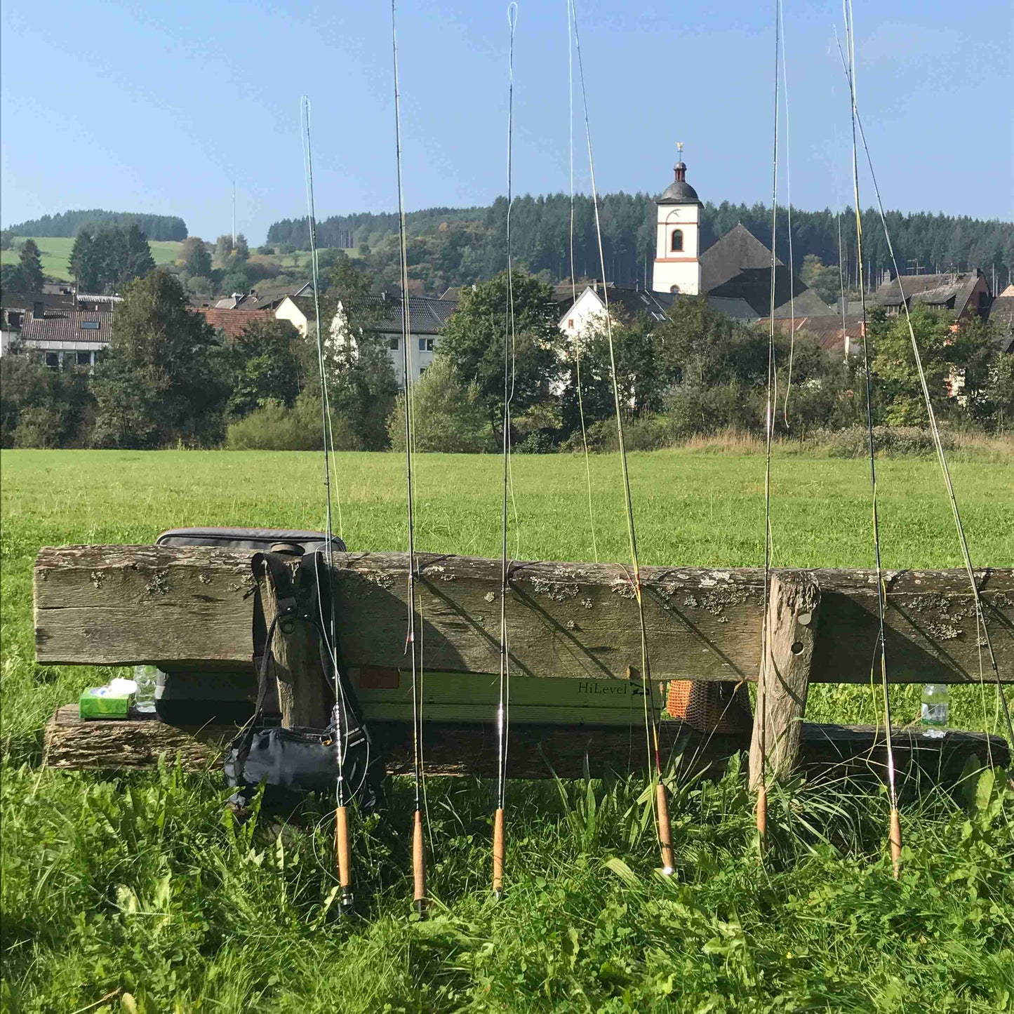 zu sehen sind 7 Fliegenruten, die an einer alten Holzbank lehnen