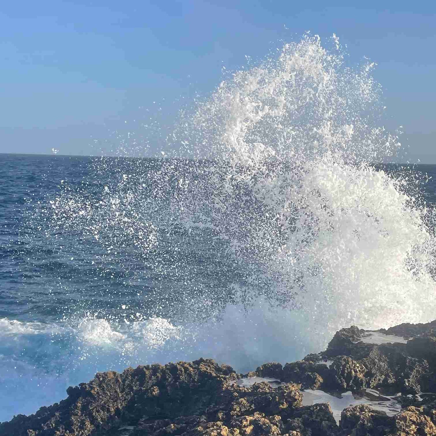 zu sehen ist eine Brandung, das Wasser schlägt gegen den Felsen.