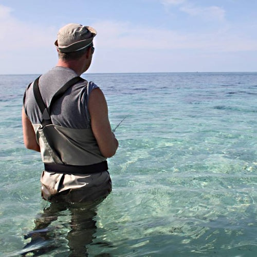 zu sehen ist ein Fliegenfischer hüfttief im Meer stehen